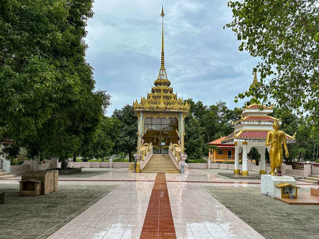 Big Buddha in Khao Lak a building with a gold roof and a statue in the middle